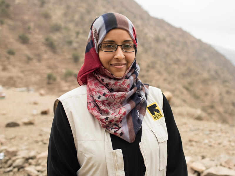Dr Rasha Rashed Dr Rasha Rashed, wearing an IRC vest, stands outside in front of a desert landscape