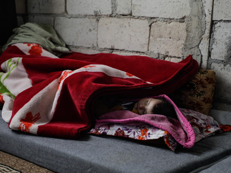 Nine-month-old baby girl Niveen, wrapped in heavy blankets, sleeps on a mat on the floor of an unfinished building in Syria.