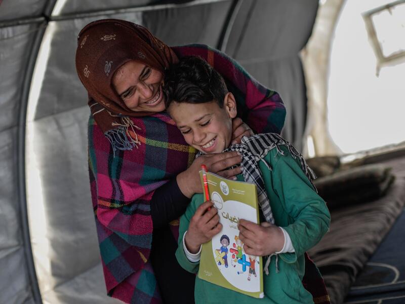 Sundus and her son Omar Sundus stands behind her son Omar. They are both laughing.