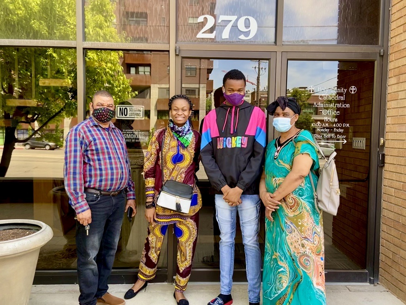 Family received their first COVID-19 vaccines Naomi and Nasse stand with their father (on the left) and mother (on the right), wearing colorful clothing and smiles.