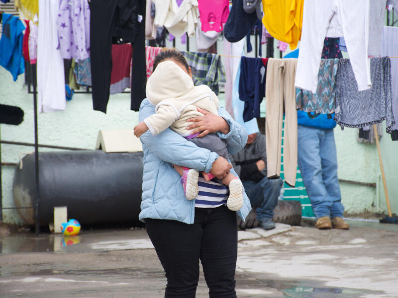 Alma, una solicitante de asilo de Guatemala, con su hija en un refugio apoyado por el IRC en México. Alma, una solicitante de asilo de Guatemala, con su hija pequeña en un refugio apoyado por el IRC en México. Ella sostiene a su hija mientras se seca la ropa cerca de ellos.