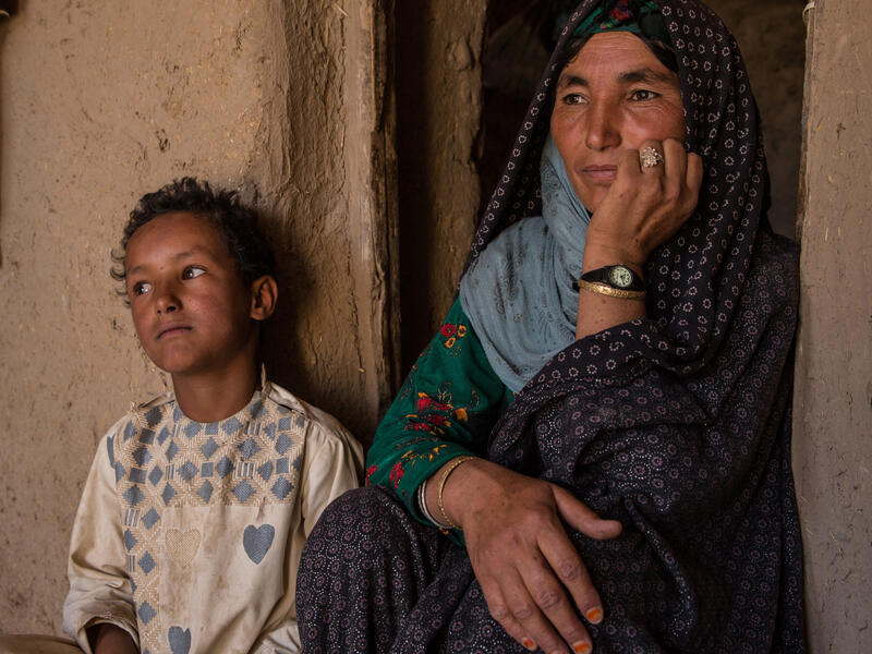 Dunya, an IRC client and mother, with her son, Juma. A mother sits against a wall next to her 7-year-old son.