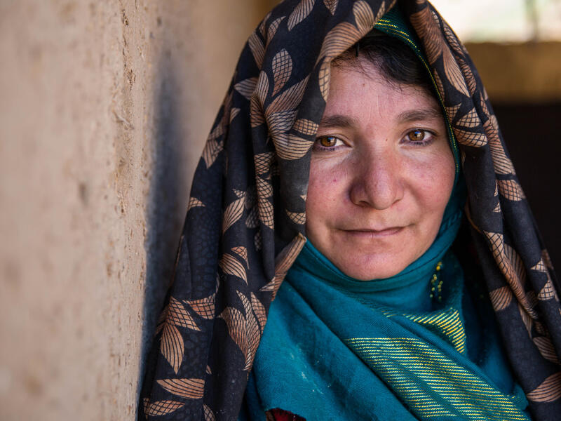 An Afghan mother of four who received cash assistance from the IRC An Afghan woman looks at the camera while standing against a wall