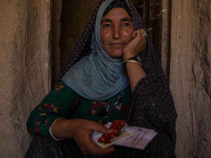 The IRC is helping Afghans like this 35-year-old widow access health care and prescriptions. A 35-year-old Afghan widow sits in a doorway holding packets of medication she was able to get with the IRC's support.