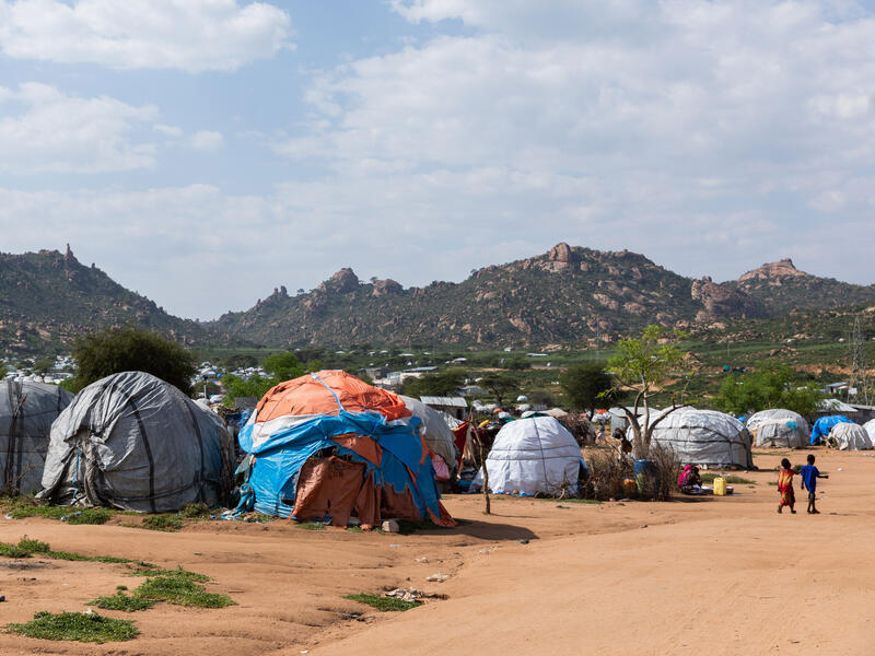 Qoloji IDP camp in the Somali region of Ethiopia. A landscape photo of tents with mountains in the distance.