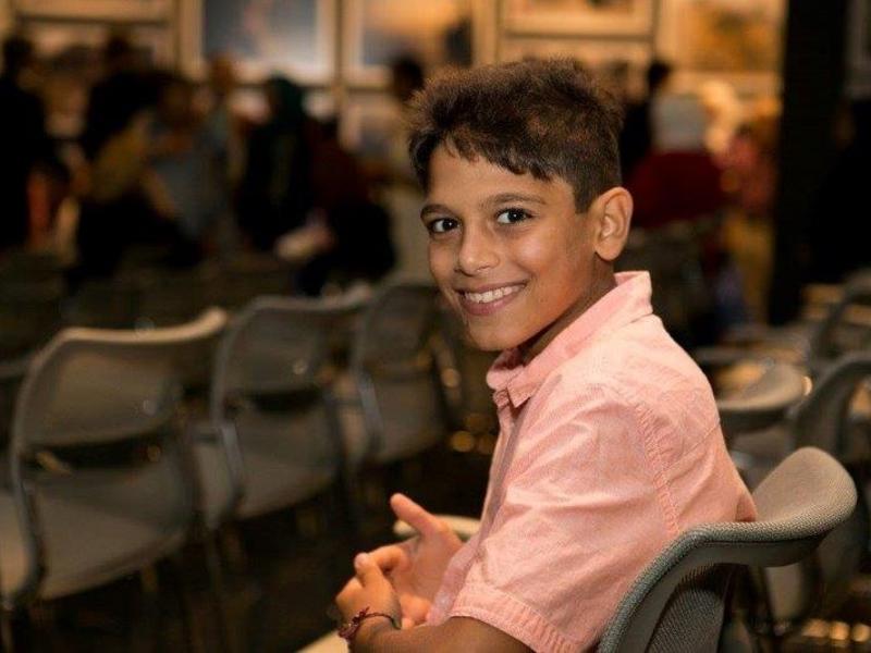 Syrian Boy at UN Refugee Event in Los Angeles Syrian boy sitting in chair, smiling, at a UN Refugee Event in Los Angeles