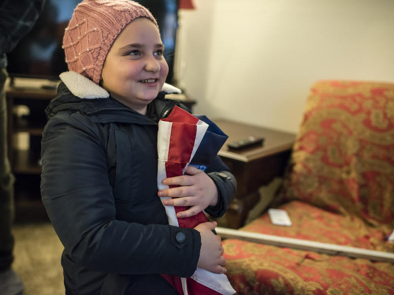 11-year-old Alaa holds a folded American flag 11-year-old Alaa holds a folded American flag