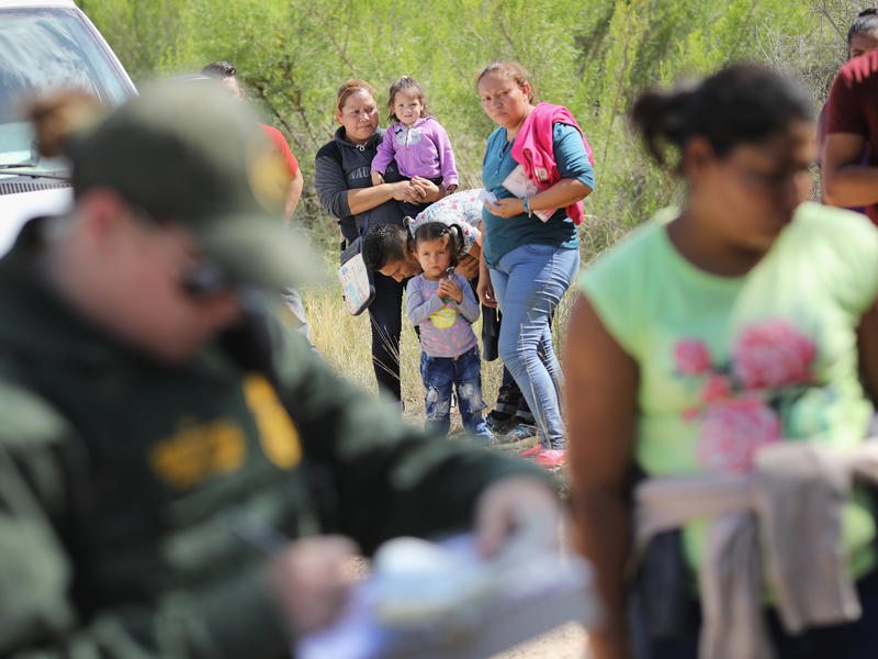 Central American asylum seekers wait as U.S. Border Patrol agents take groups of them into custody near McAllen, Texas. 