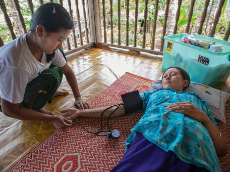 An IRC health worker takes the blood pressure of a patient (name not provided) in a refugee camp in Thailand. An IRC health worker takes the blood pressure of a female patient lying on a mat on the floor in Thailand.