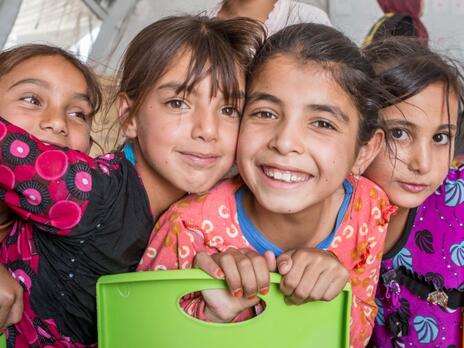 Girls taking part in an IRC program stand near one another to smile and post for a camera 
