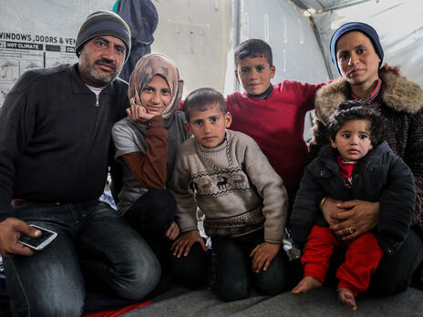 Hani, his wife and their four children, bundled in winter clothes, sit in a tent in a refugee camp in Greece.