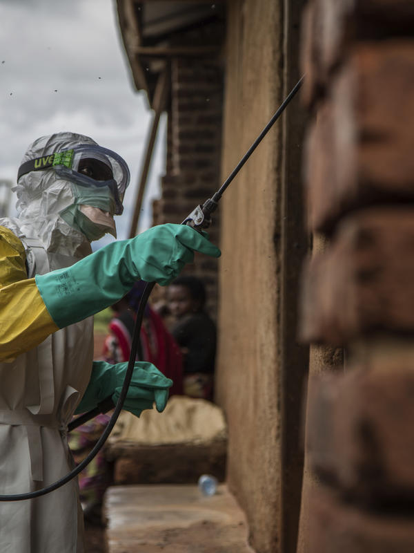 A health worker sprays disinfectant on Case Du Salut health facility