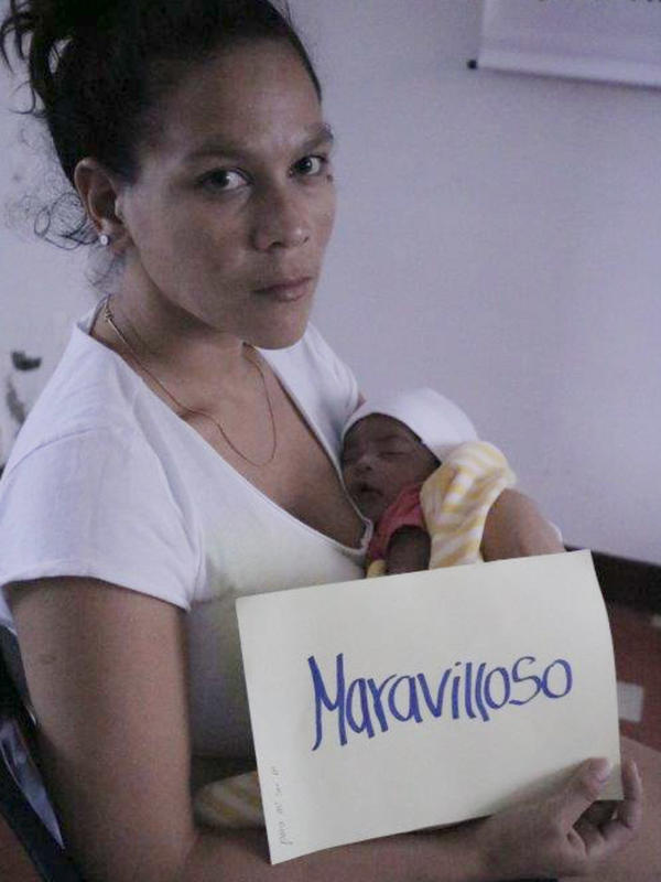 Verónica Andrade, a Venezuelan migrant in Colombia and a new mother, holds a sign saying “Maravilloso” (or “Wonderful”). Verónica Andrade, a Venezuelan migrant in Colombia and a new mother, holds a sign saying “Maravilloso” (or “Wonderful”) along with her new baby while looking at the camera.