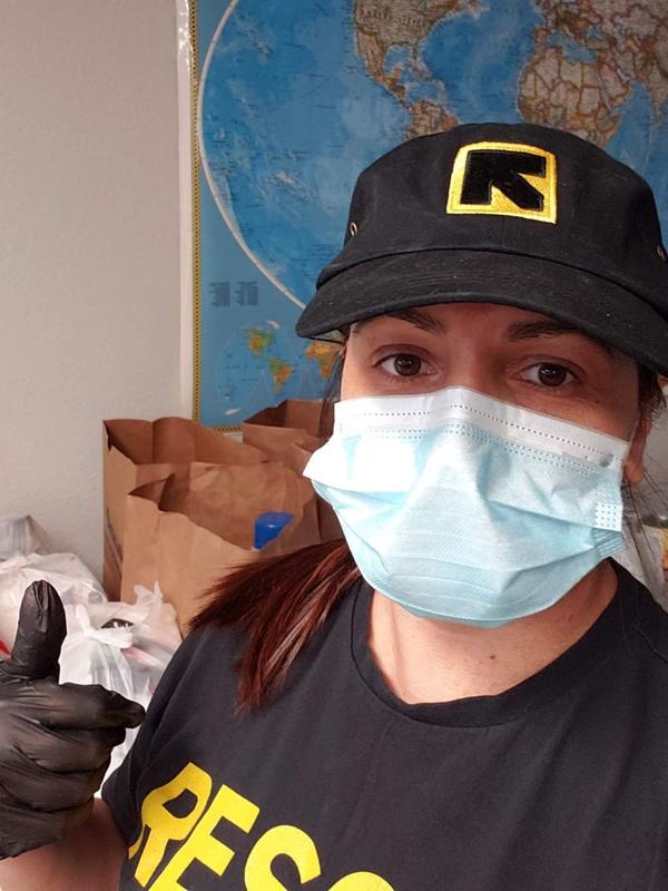 Meheria Habibi looks at the camera and gives a thumbs up. She is wearing a mask, as well as an IRC hat and t-shirt. 