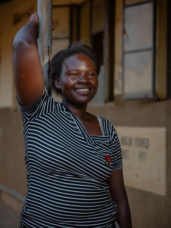 Jackie leans against a pole outside, smiling. 