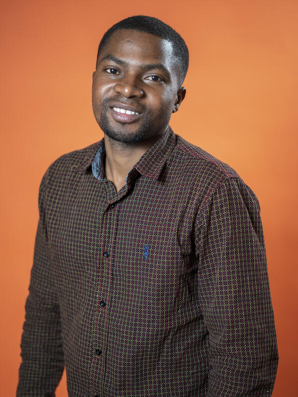 Robert Sebatware poses in front of an orange background 