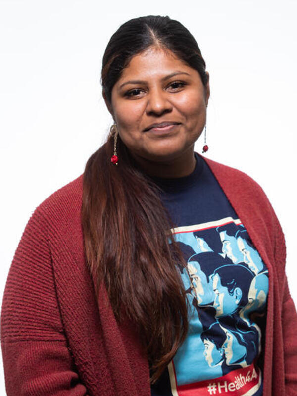 Lupe, a DACA recipient Lupe, a DACA recipient is wearing a red sweater with her hair in a ponytail. She is looking at the camera and standing in front of a white background.