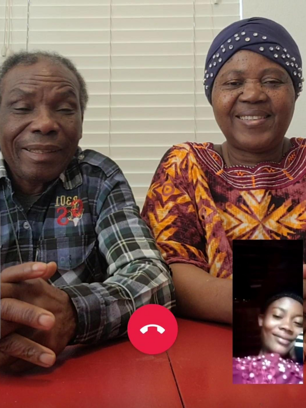 A screenshot of a smart phone, with Patrice and his wife sitting at a table and their daughter Mauwa in a small box on the lower right side of the screen
