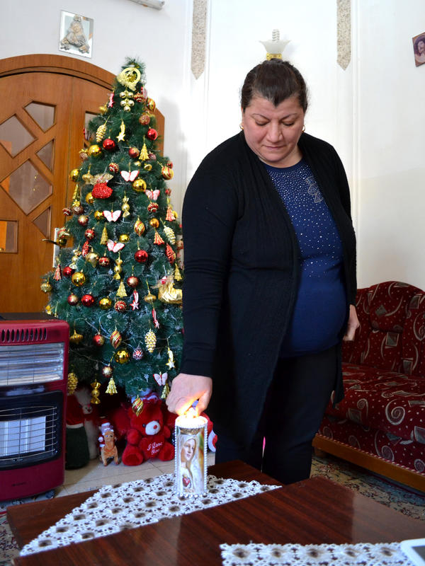 Linda Abid Younis lights a candle in her living room in Iraq Linda Abid Younis lights a religious candle at her home