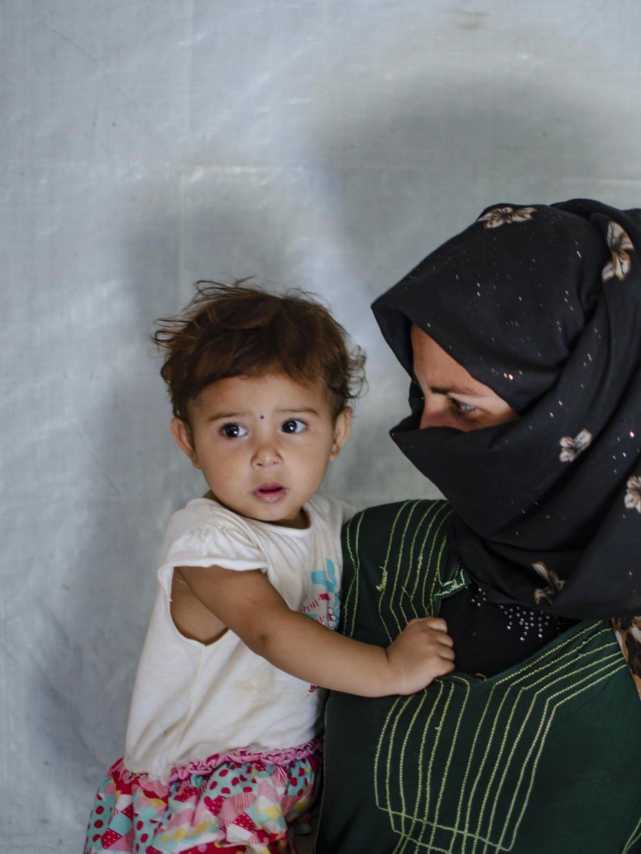 a veiled woman carries her baby son