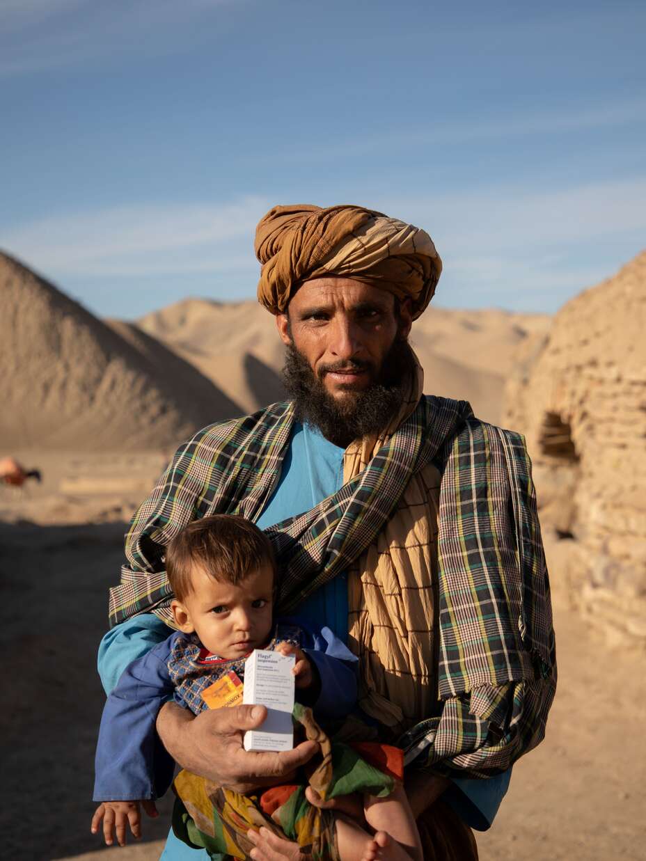 Abdul Haq holding his 10 month old son, Shams Ullah, outside the mobile health clinic after getting his medical exam.