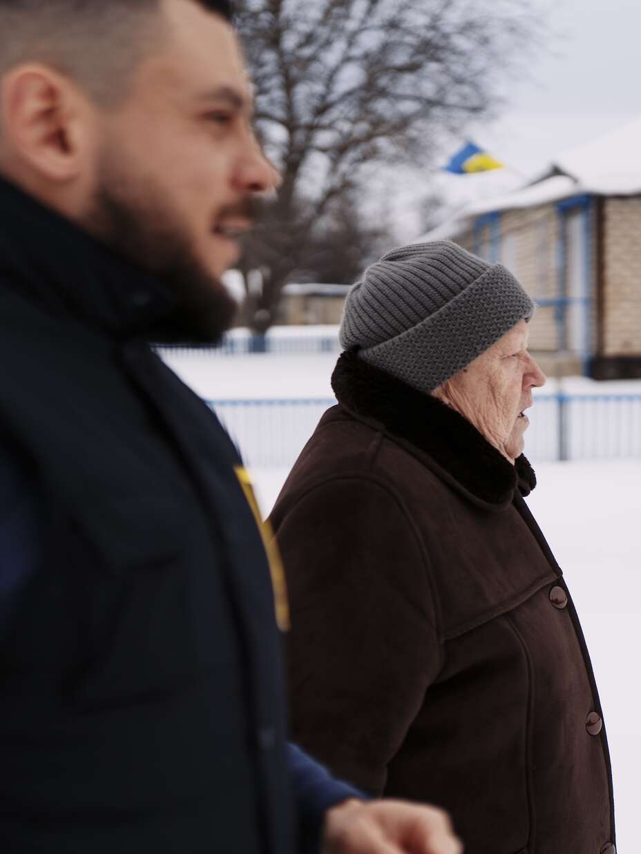 Mariia, an elderly woman, walks beside an IRC doctor along a rural road in Ukraine’s Kharkiv region.