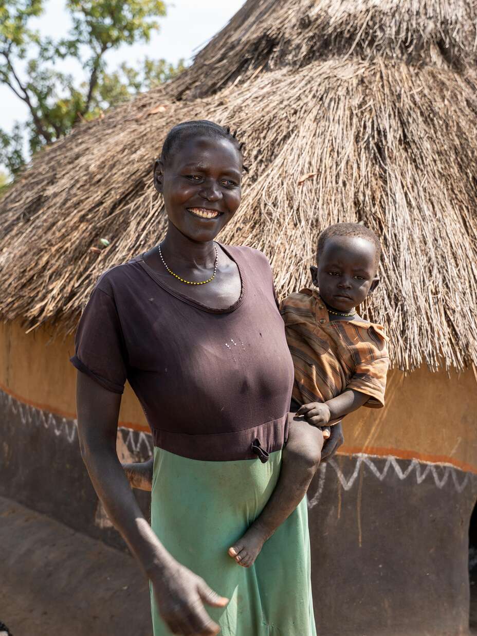 Elizabeth smiling outside her temporary home with her healthy baby boy. 