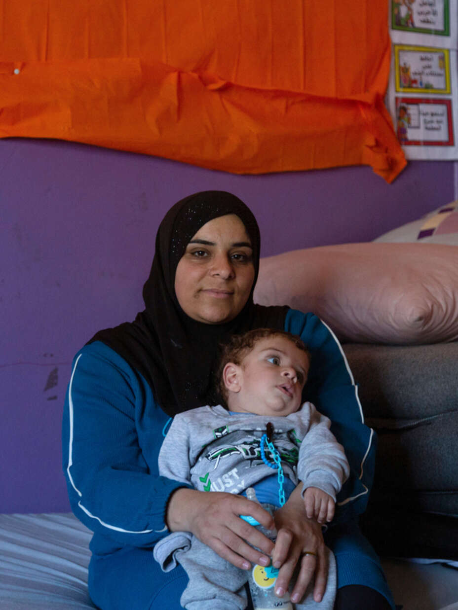 Mamma i Libanon sitter med sin son i famnen 