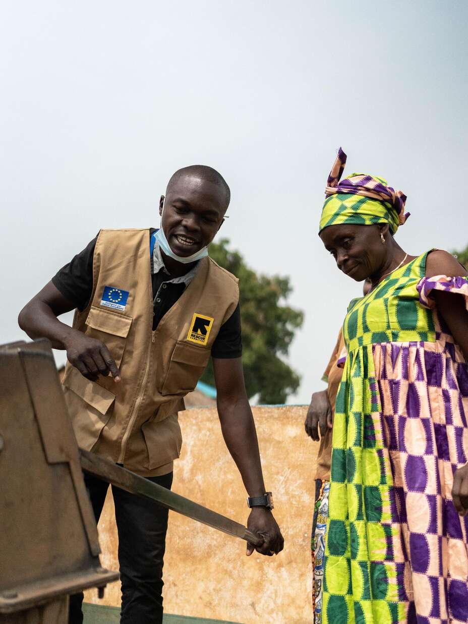 An IRC staff member teaches Adrienne how to use the new well properly