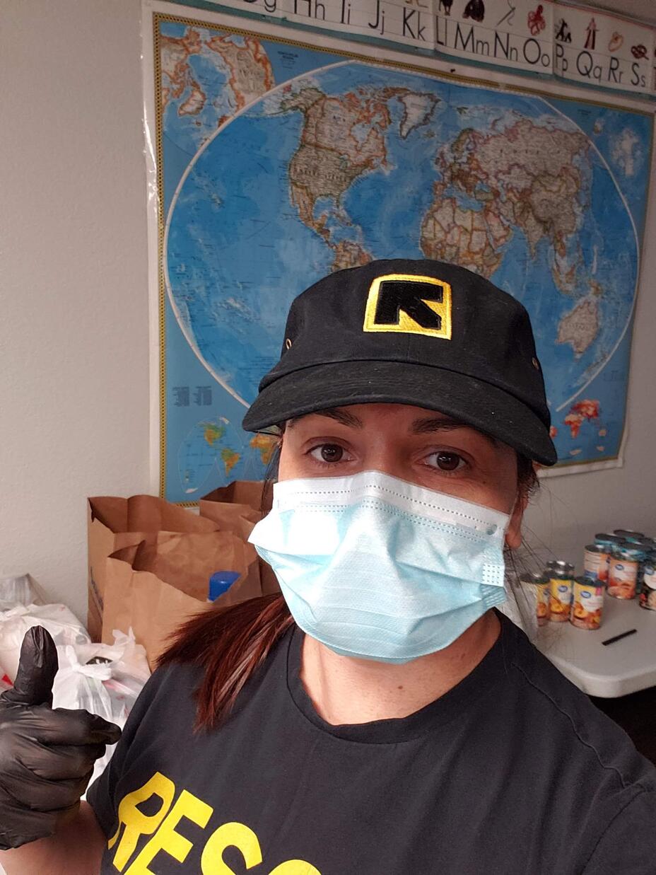 Meheria Habibi looks at the camera and gives a thumbs up. She is wearing a mask, as well as an IRC hat and t-shirt.