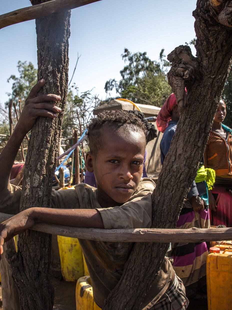 Aman Yassin, 12, waits at a water point to fill his jerrycans 