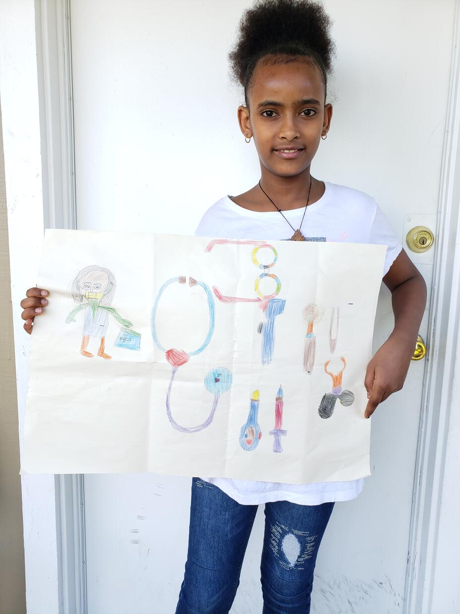 Delina, an 8-year-old girl from Eritrea, stands outside her new home in Seattle holding her drawing of a doctor with her medical implements.