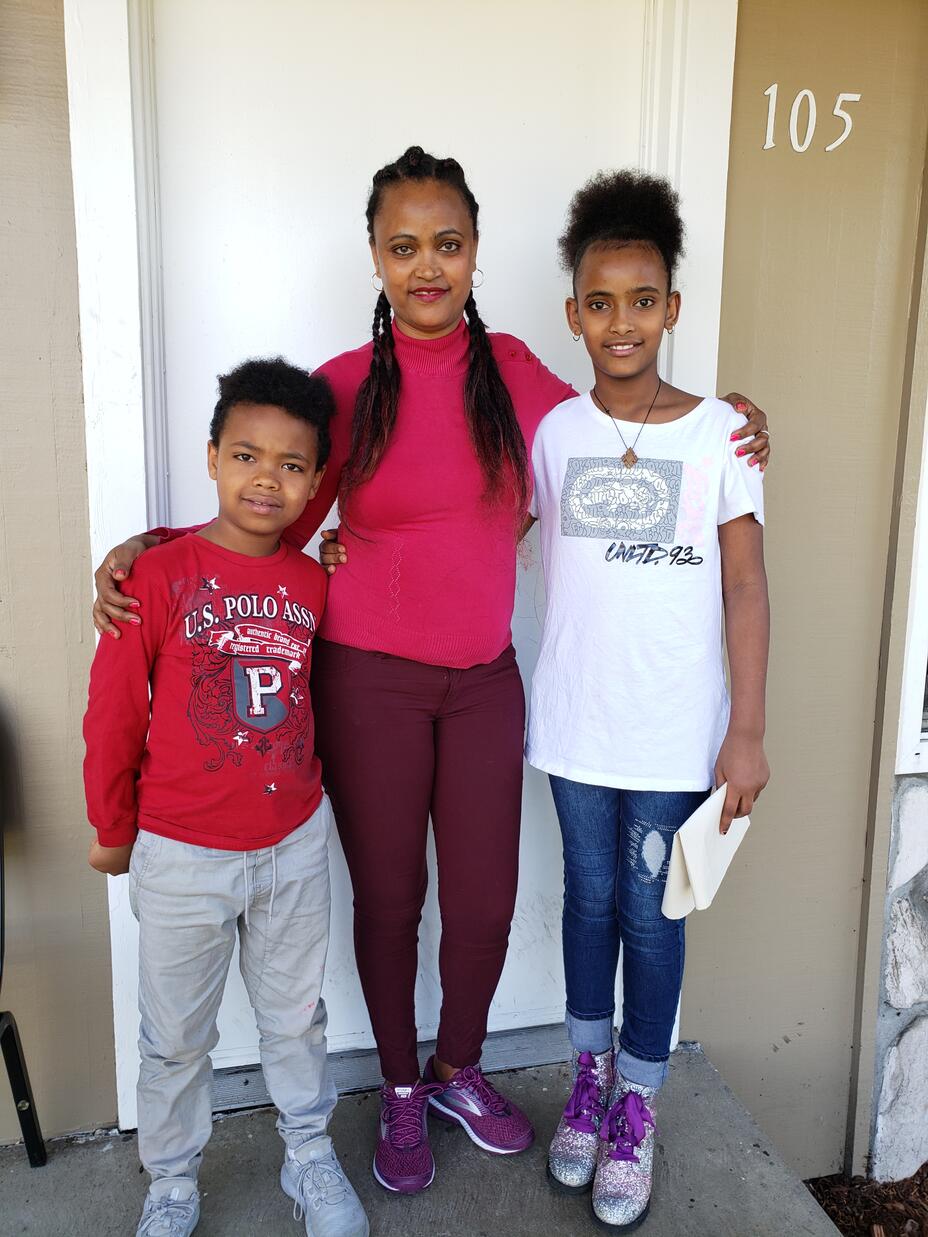 Eritrean mother Abrehet stands with her arms around the shoulders of her 5-year-old son Kudus and daughter Delina, 8. 