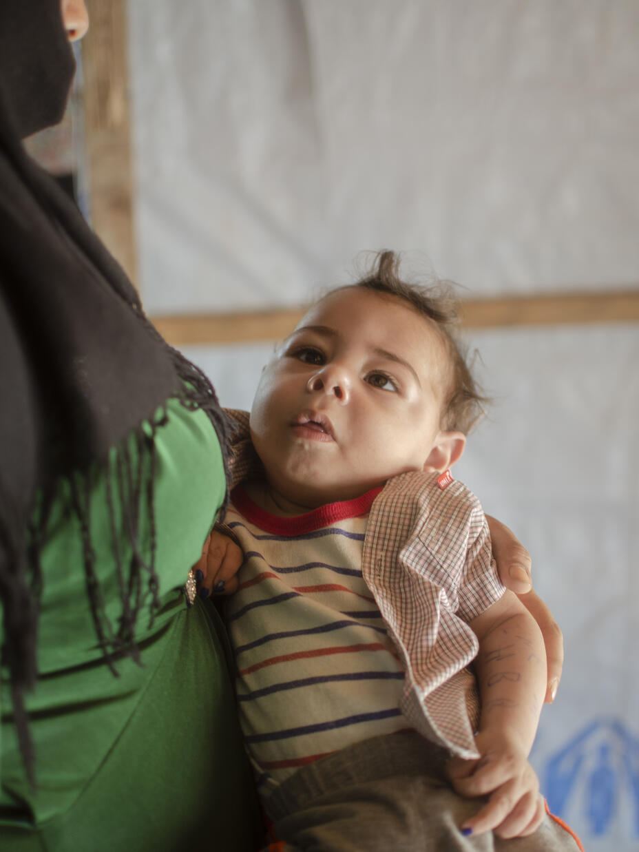 Syrian mother and refugee, Khitam, holds her baby son Brahim 