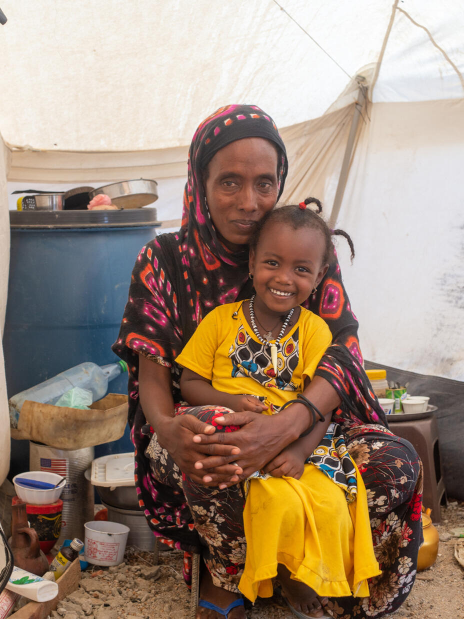 Mulu crouches on the floor of a tent, holding her daughter, after fleeing the Tigeay crisis,