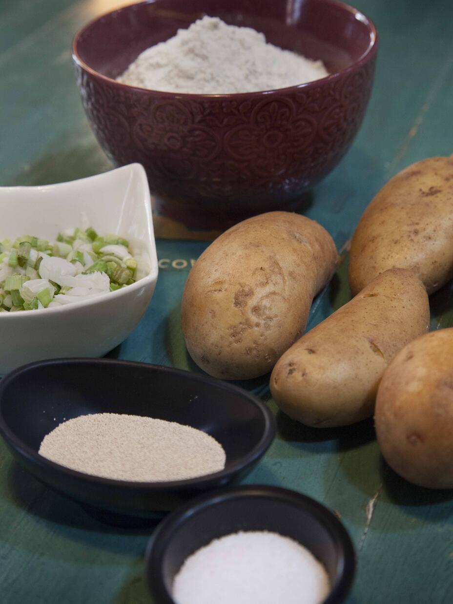 Ingredients for Afghan Bolani arranged a on a table with a green tablecloth. They include potatoes and salt. 