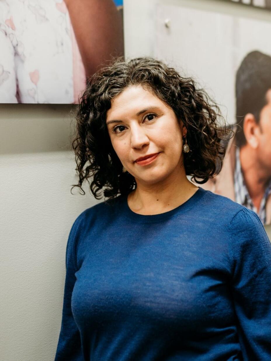 Natalie El-Deiry, executive director at the IRC in Salt Lake City, posing in front of a wall with portraits in the background.
