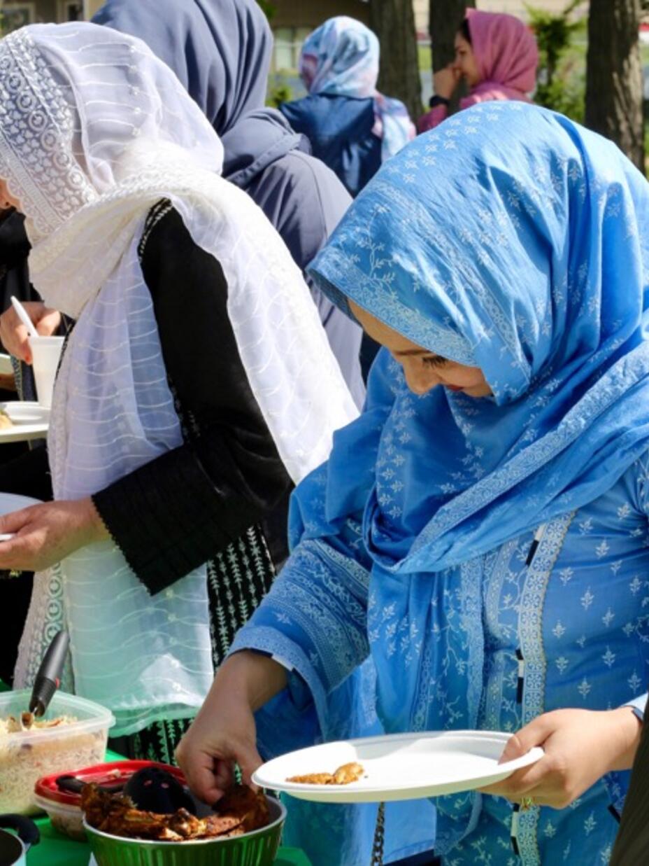 Afghan women dressed in head scarves reaching for food during a mothers day celebration