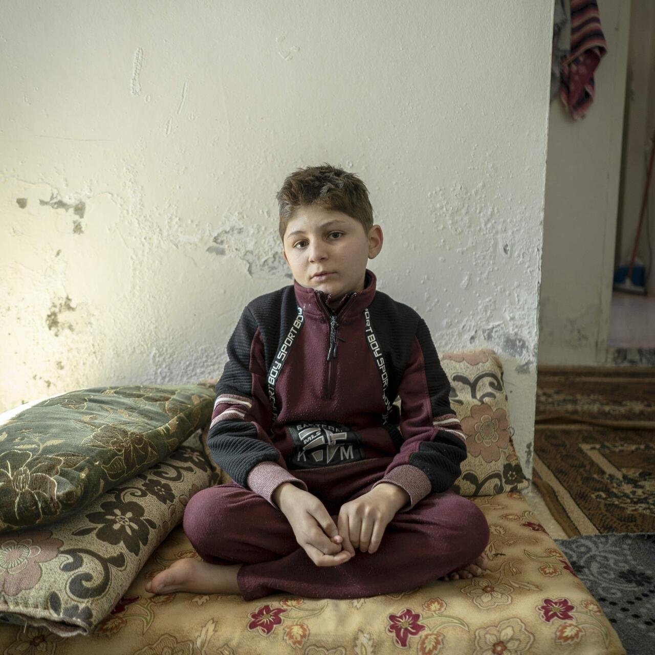 A boy sitting on a matress on the floor