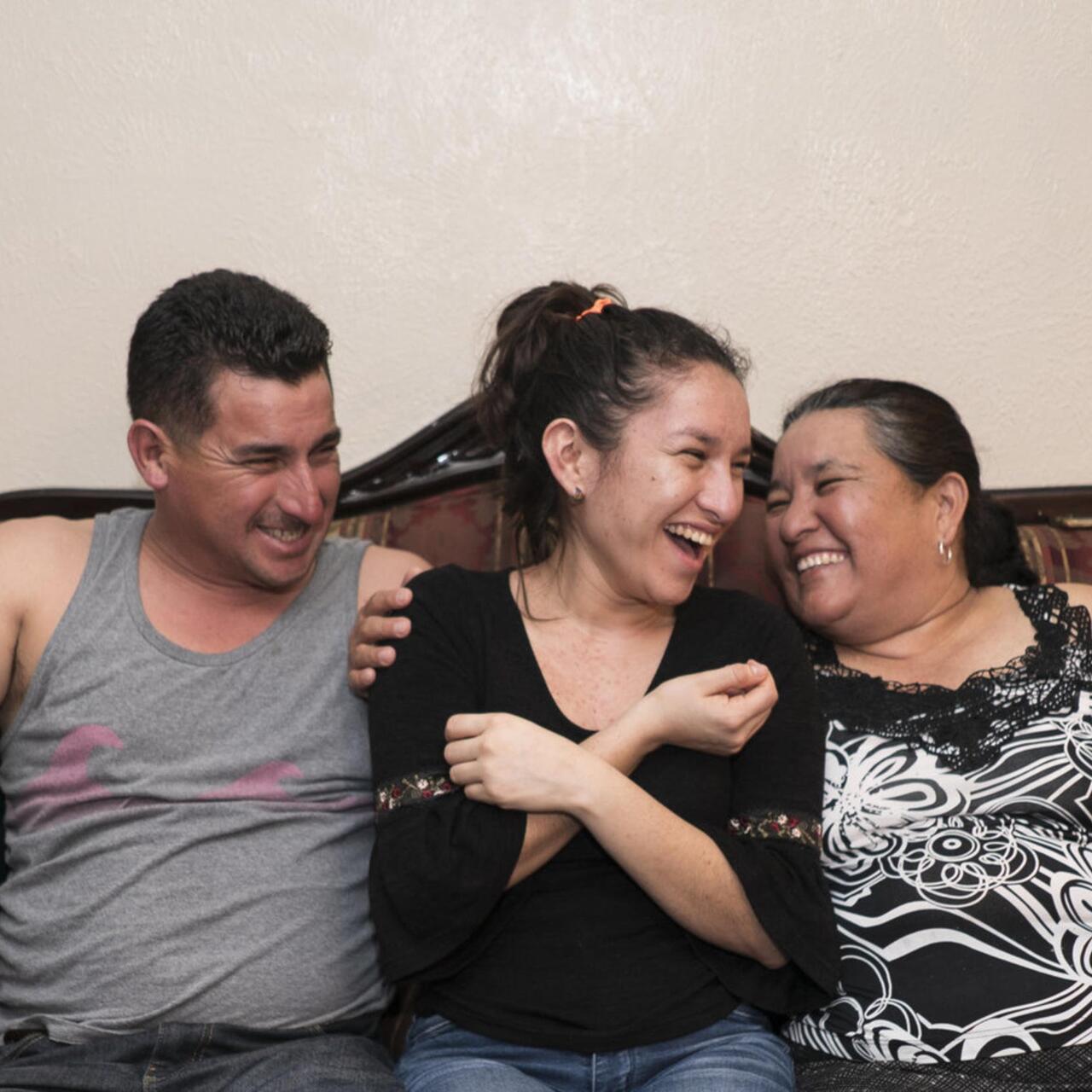 three laughing people sitting on a sofa