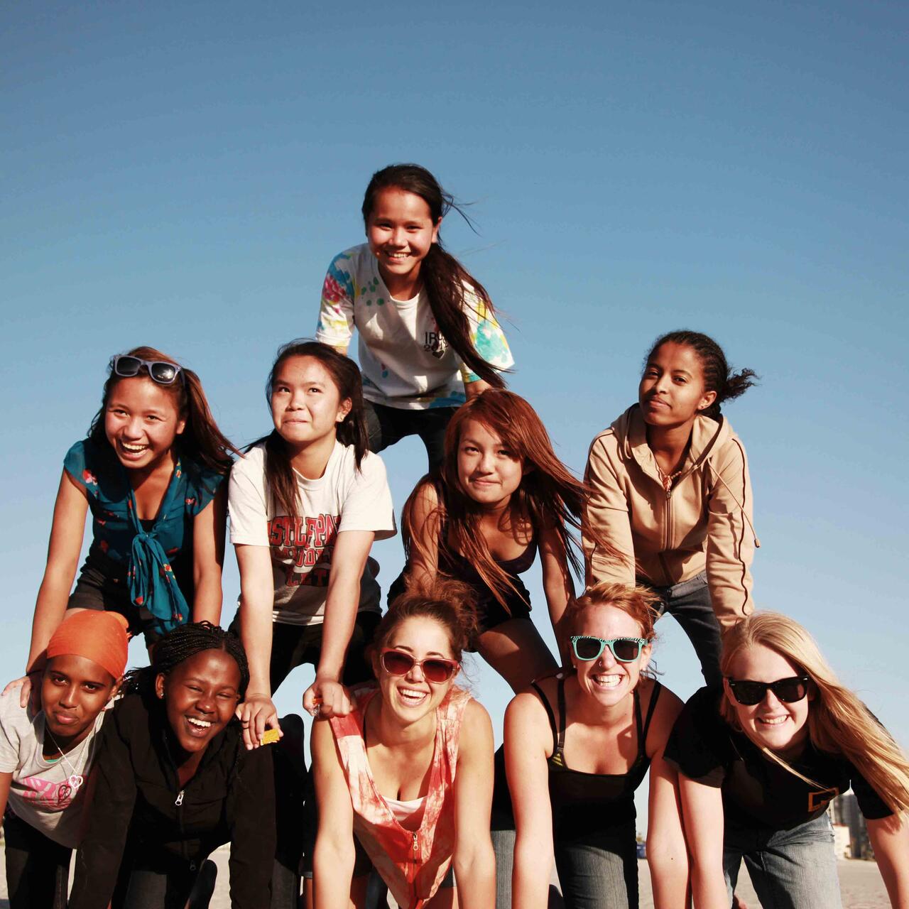 Teilnehmer*innen von International Rescue Committees „Girls Group“ an den Strand bilden eine Pyramide am Strand in San Diego. 
