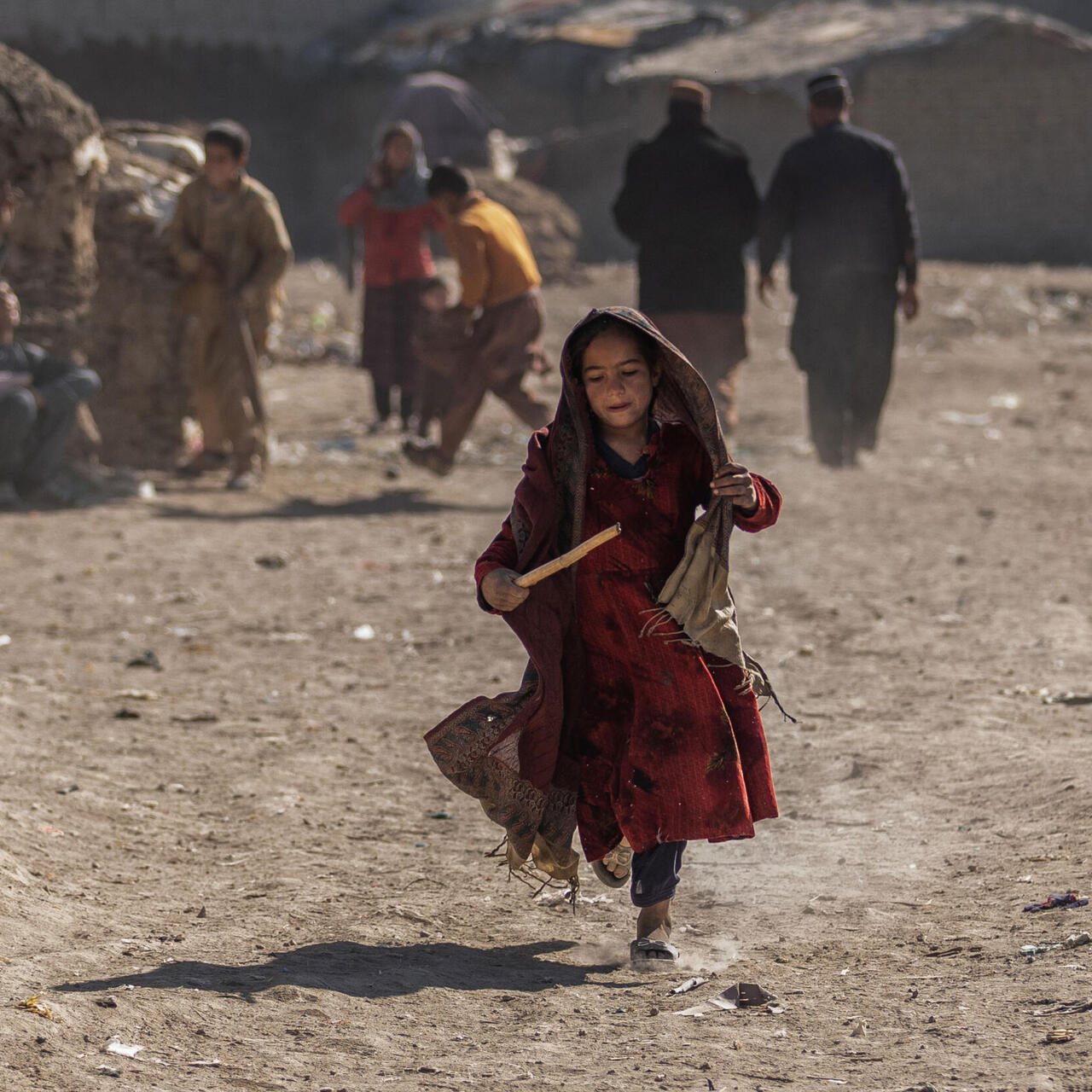 Afghan girl running with stick