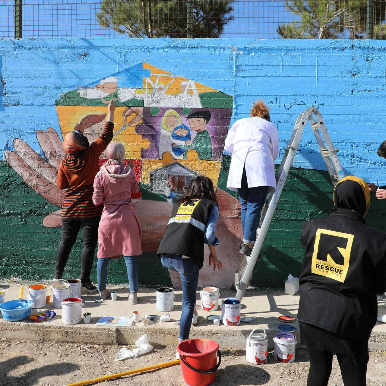 Clients working with IRC staff on a mural for the Building a Better Tomorrow Programme