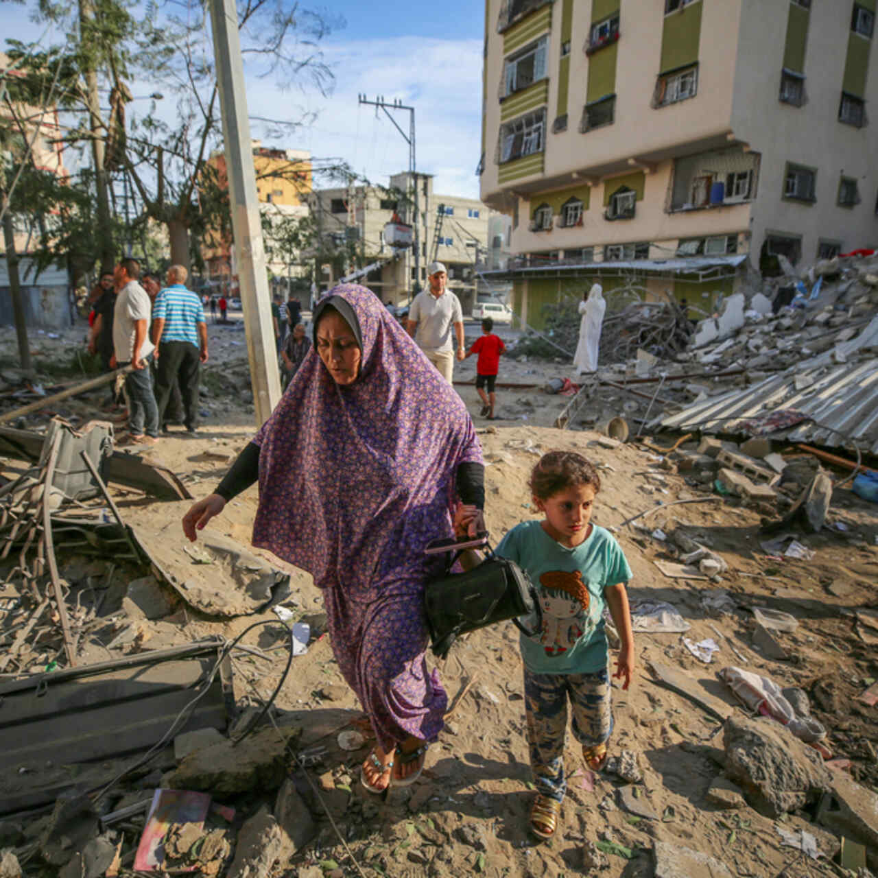 A mother and child walk through the destruction caused by Israeli air strikes in Gaza City.