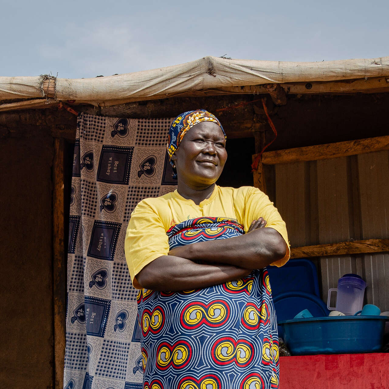 Eine Frau steht mit verschränkten Armen im Freien in Uganda.