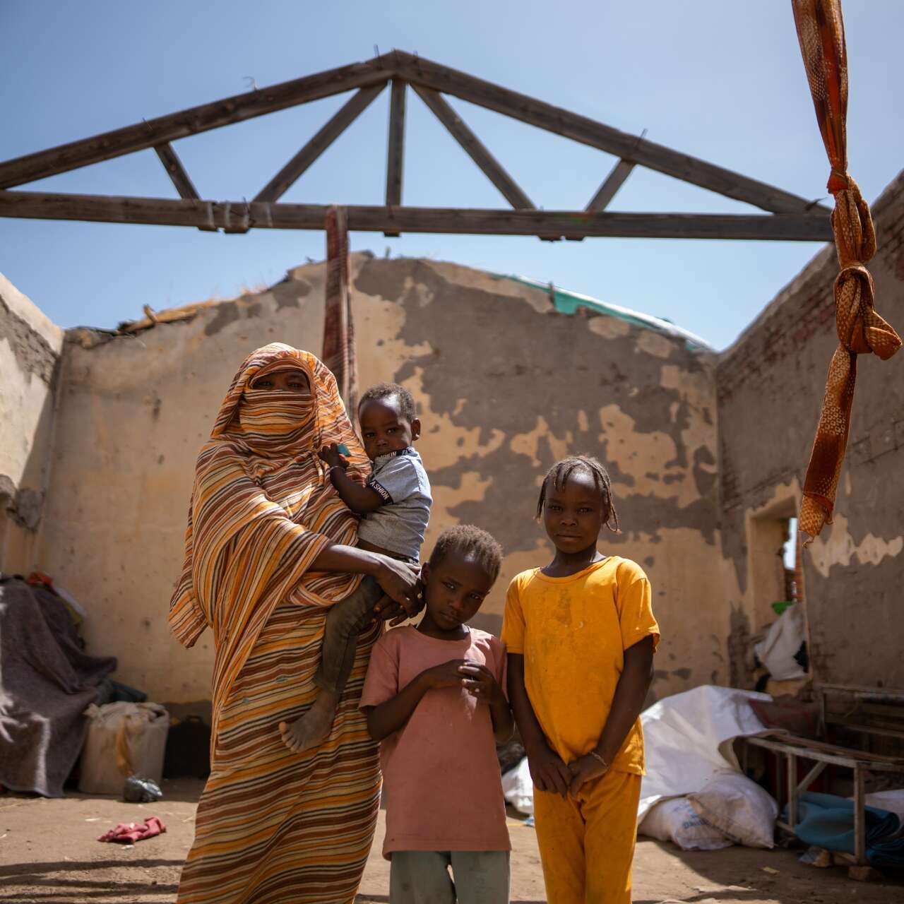 Altuma stands in her temporary house with her three children.