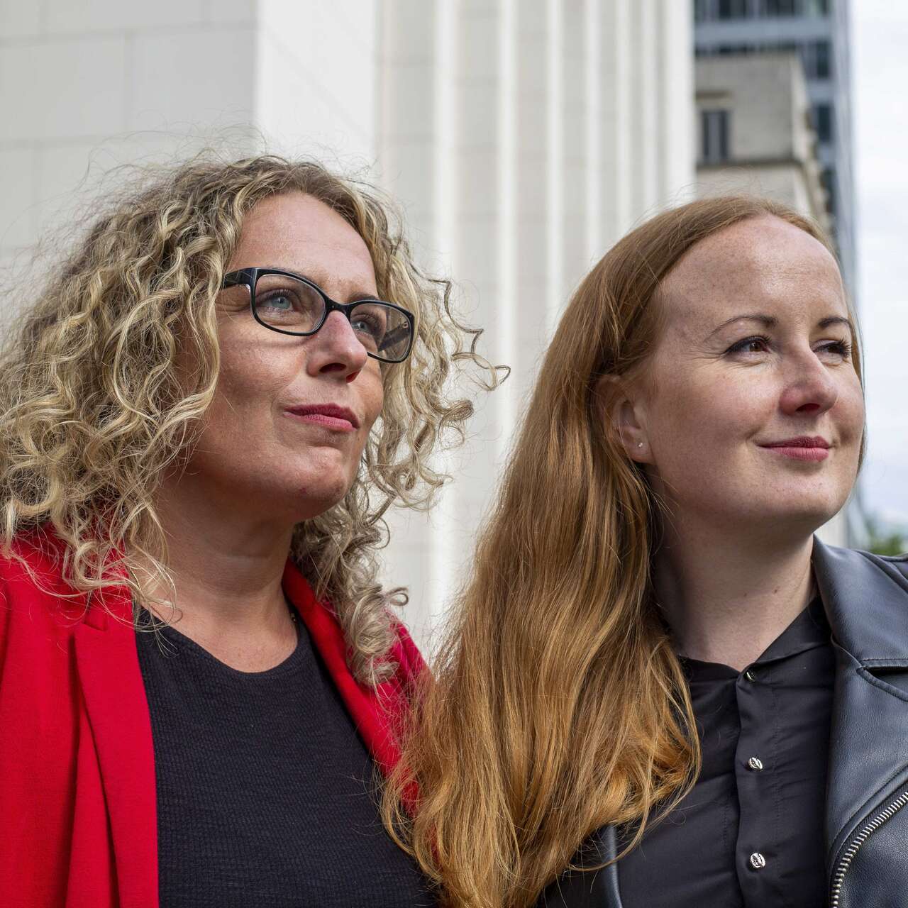 Two women look into the distance, the city in the background.