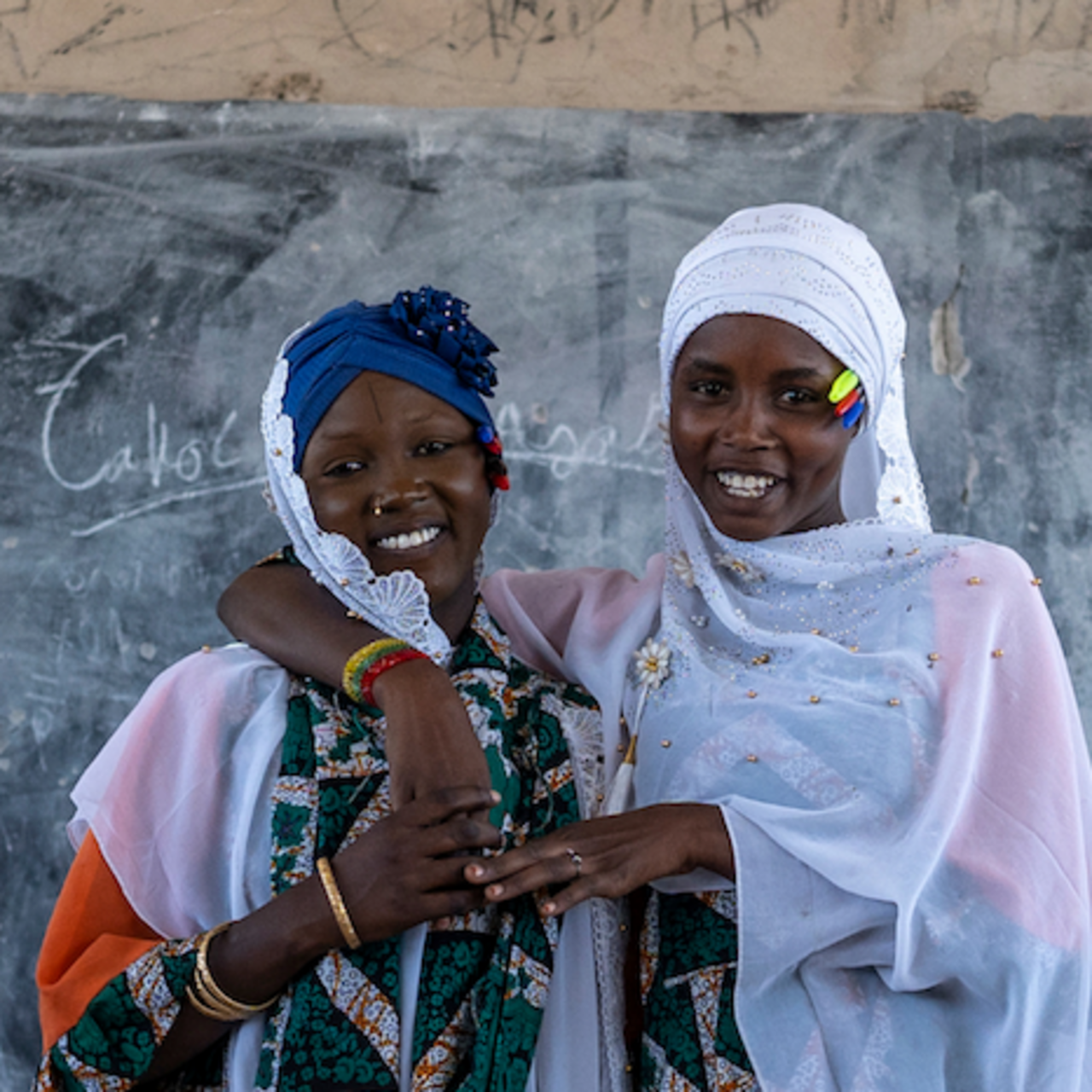 Two women in scarves looking at the camera and smiling