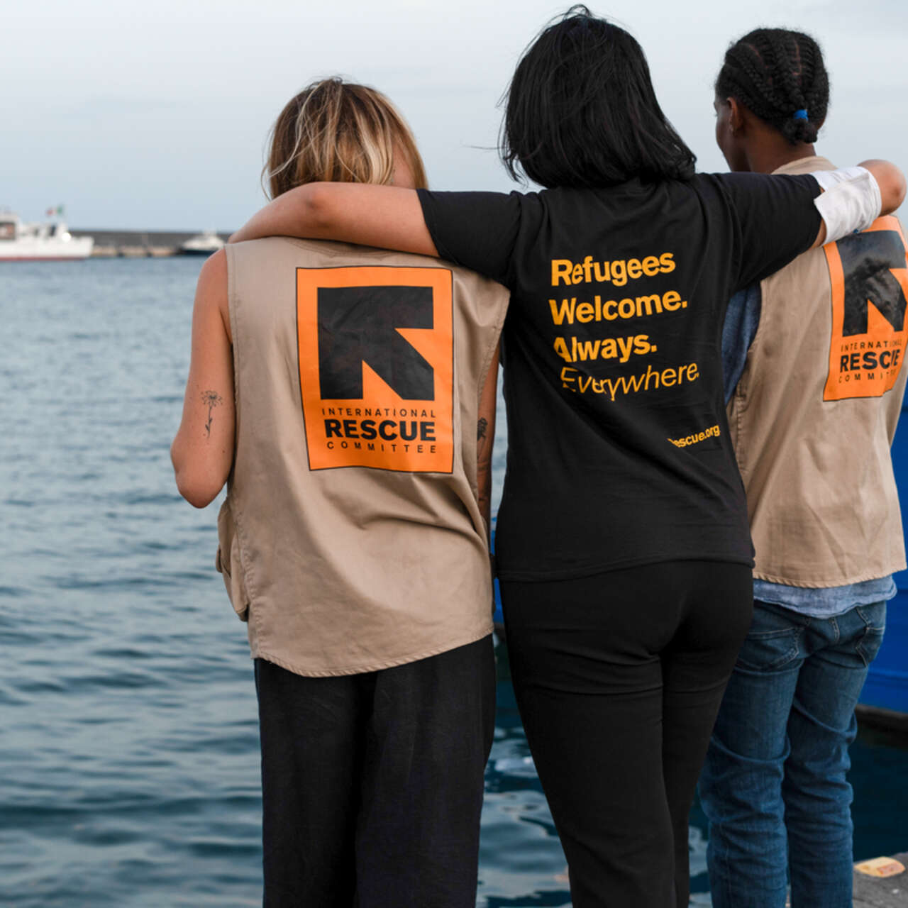 Tre personer i RESCUE-västar vid en hamn i Italien. RESCUE ger skydd och stödd till människor som överlevt resan över Medelhavet.