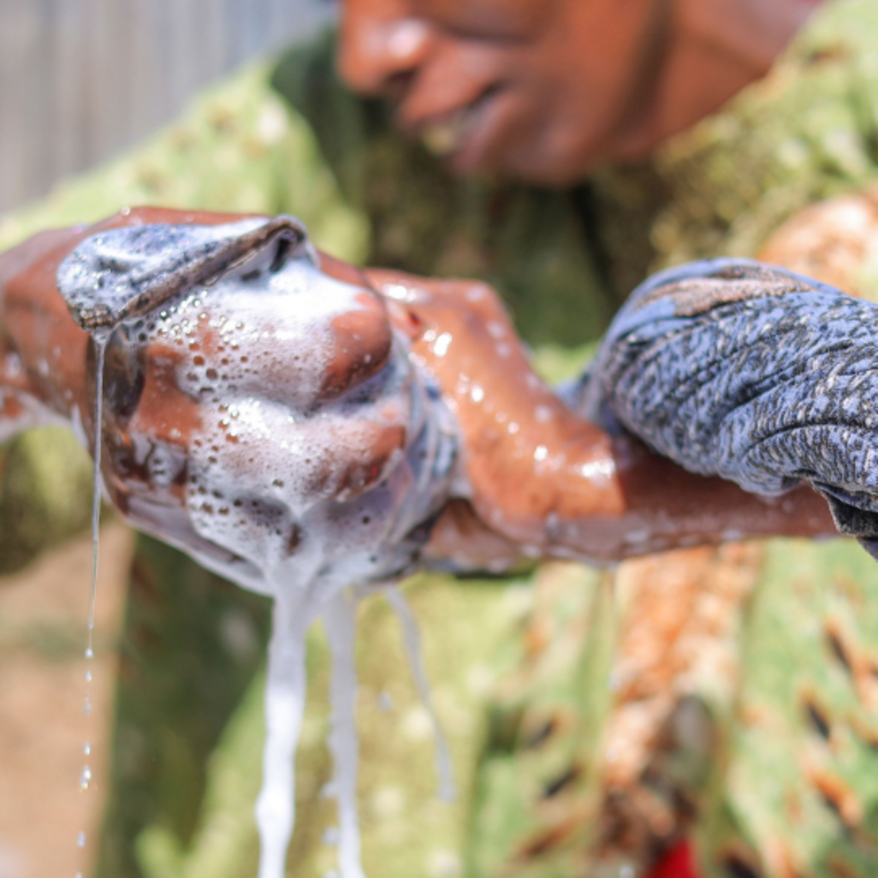 En kvinna tvättar kläder i en balja med vatten